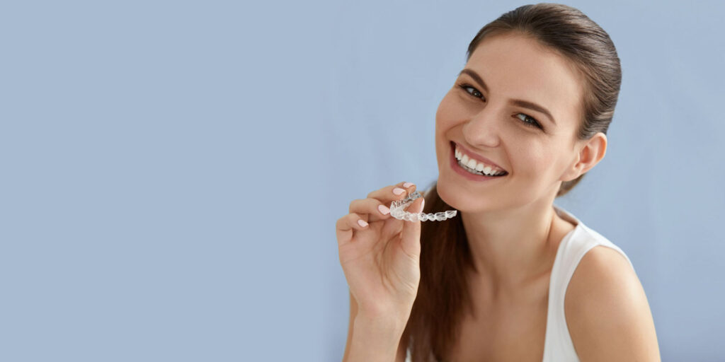 dental patient smiling holding Invisalign clear aligners