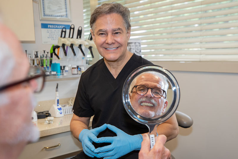 Patient smiling confidently in the mirror with doctor within the dental practice