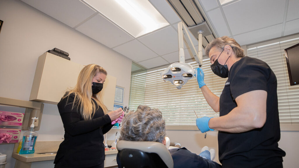 doctor and staff member performing dental procedure with patient